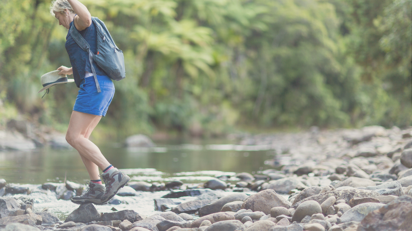 A hiker exploring a shallow stream near a camper van, embracing adventure during an off-grid digital nomad trip.